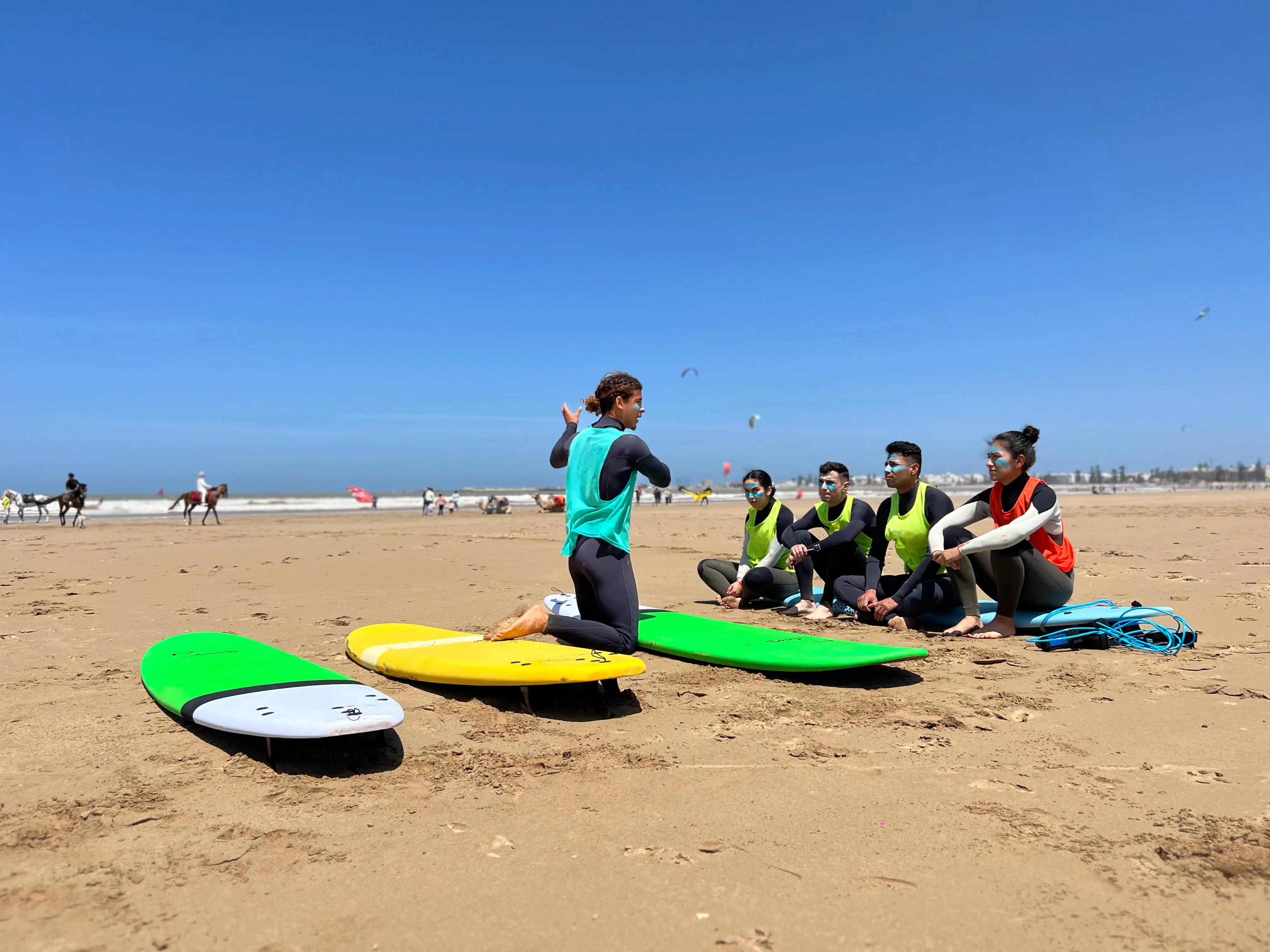 Moniteur surf Bluboarding expliquant le spot et les conditions de vagues aux élèves sur la plage près de Dakhla avant un cours de surf semi-privé.