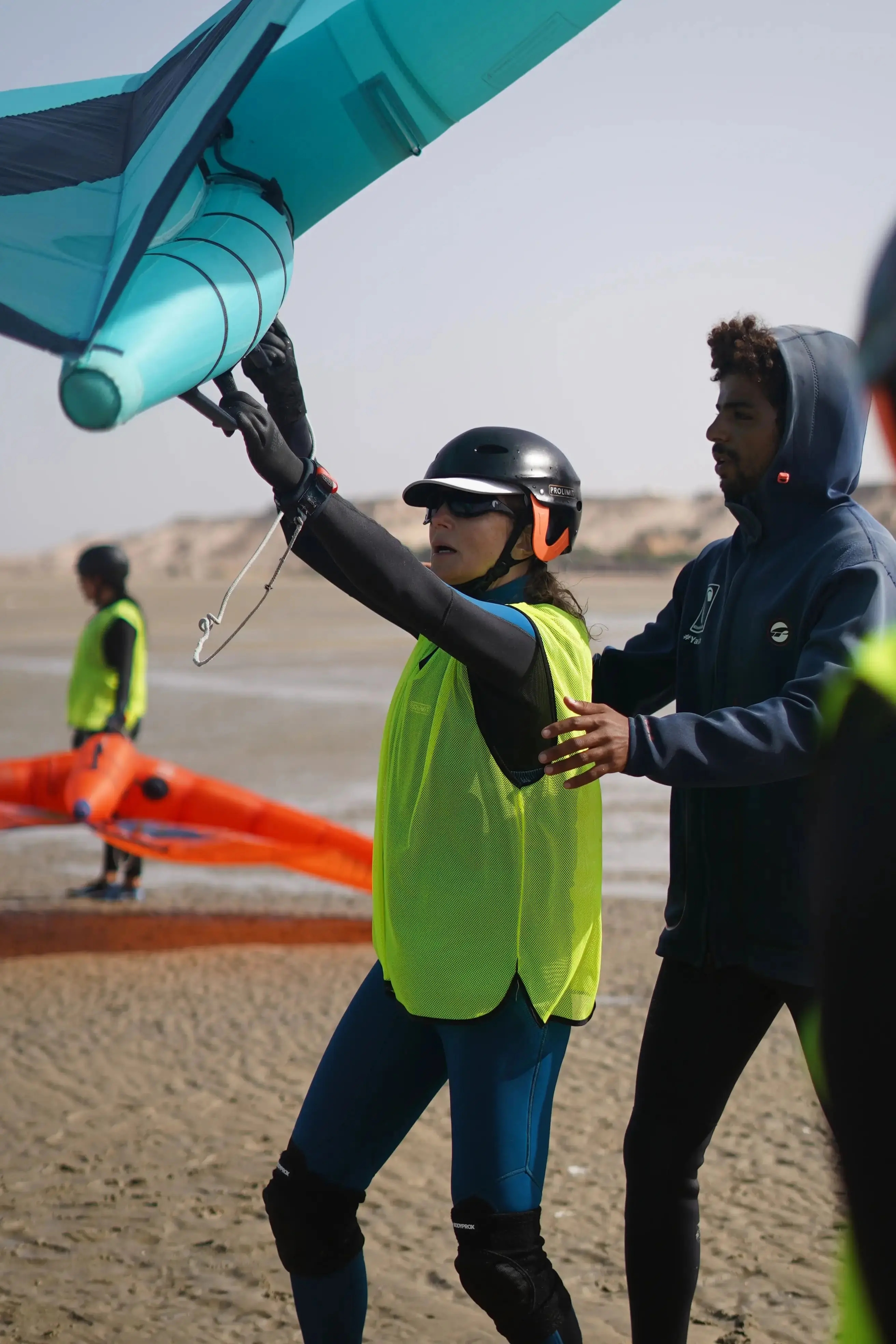 Moniteur wingfoil Bluboarding expliquant la technique de l'aile à un groupe d'élèves sur l'eau du lagon de Dakhla lors d'un cours de wingfoil en groupe.