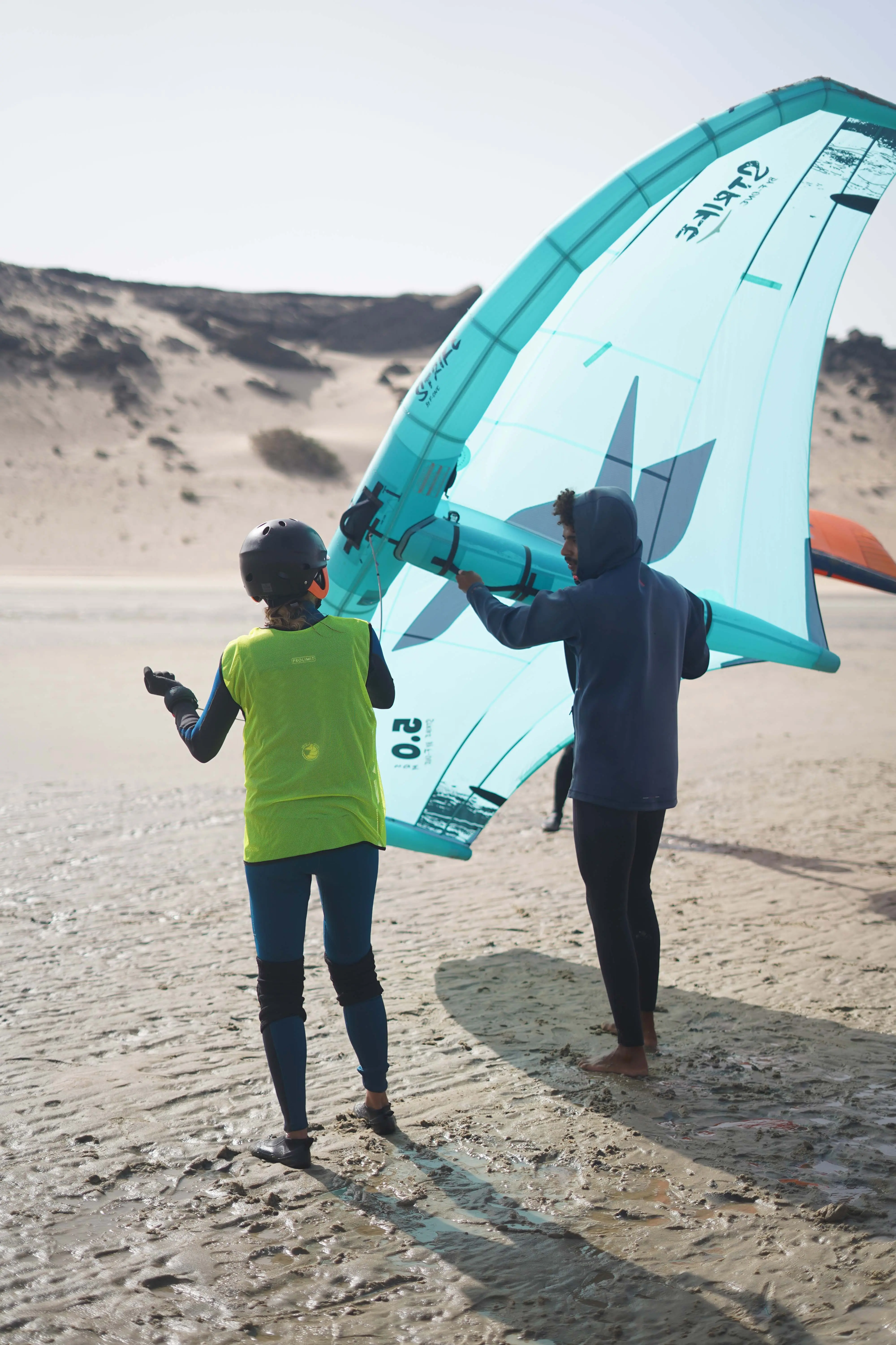 Un moniteur Blüboarding donnant un cours privé de wingfoil, enseignant à un élève comment manier l'aile sur la plage de Dakhla.