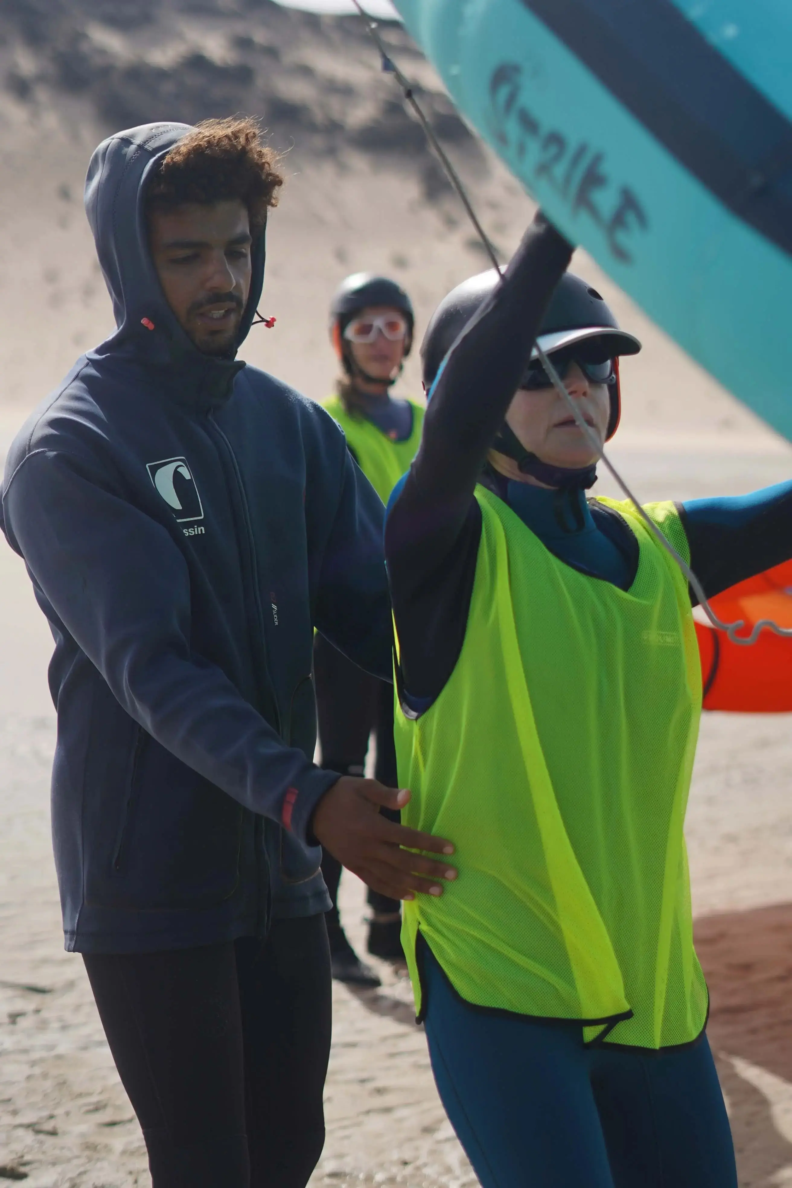 Deux amis apprenant la bonne position du corps lors d'un cours de wingfoil semi-privé avec leur moniteur à Dakhla.