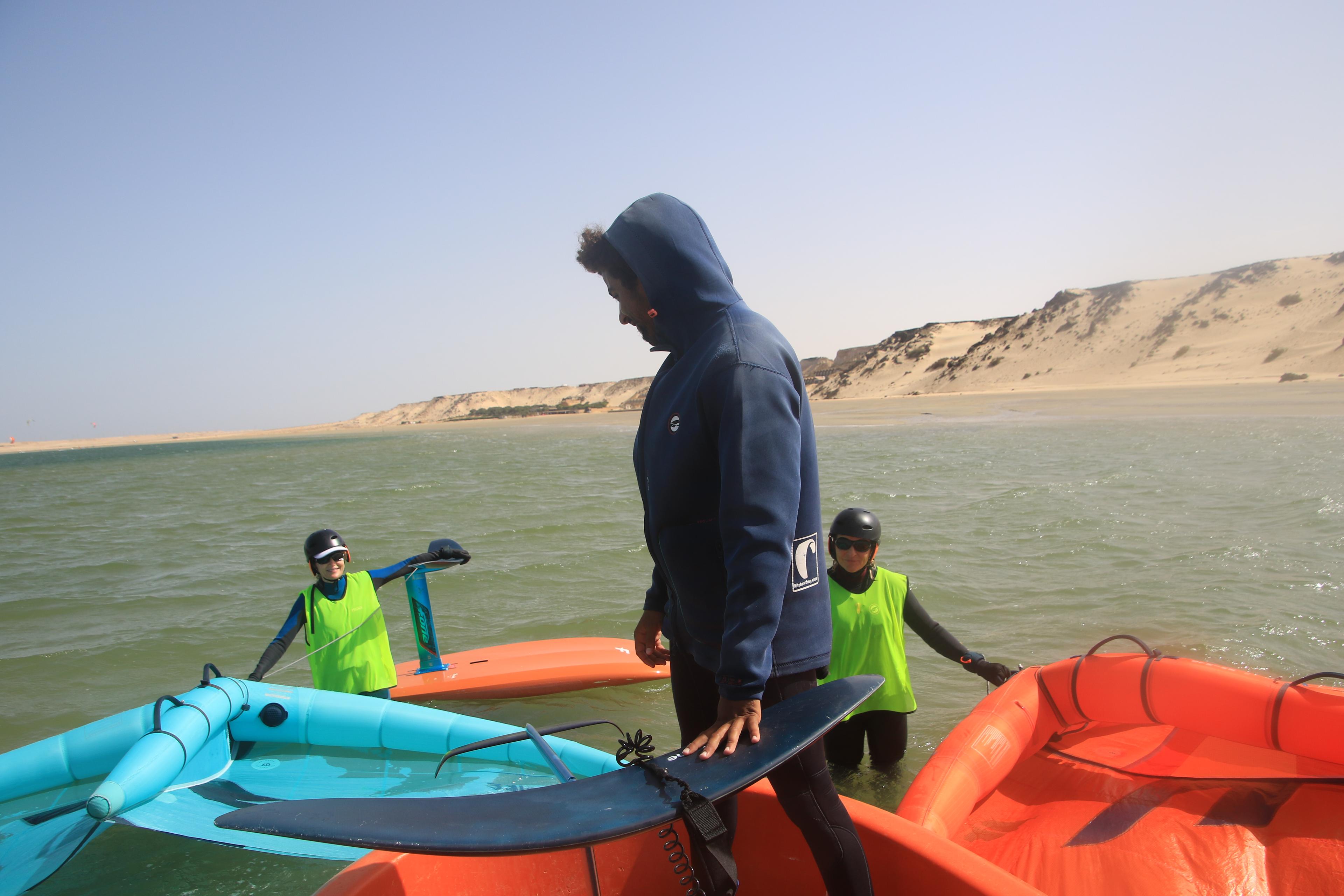 Moniteur wingfoil Bluboarding souriant sur le bateau de sécurité avec deux élèves après les avoir récupérés sur le lagon de Dakhla.