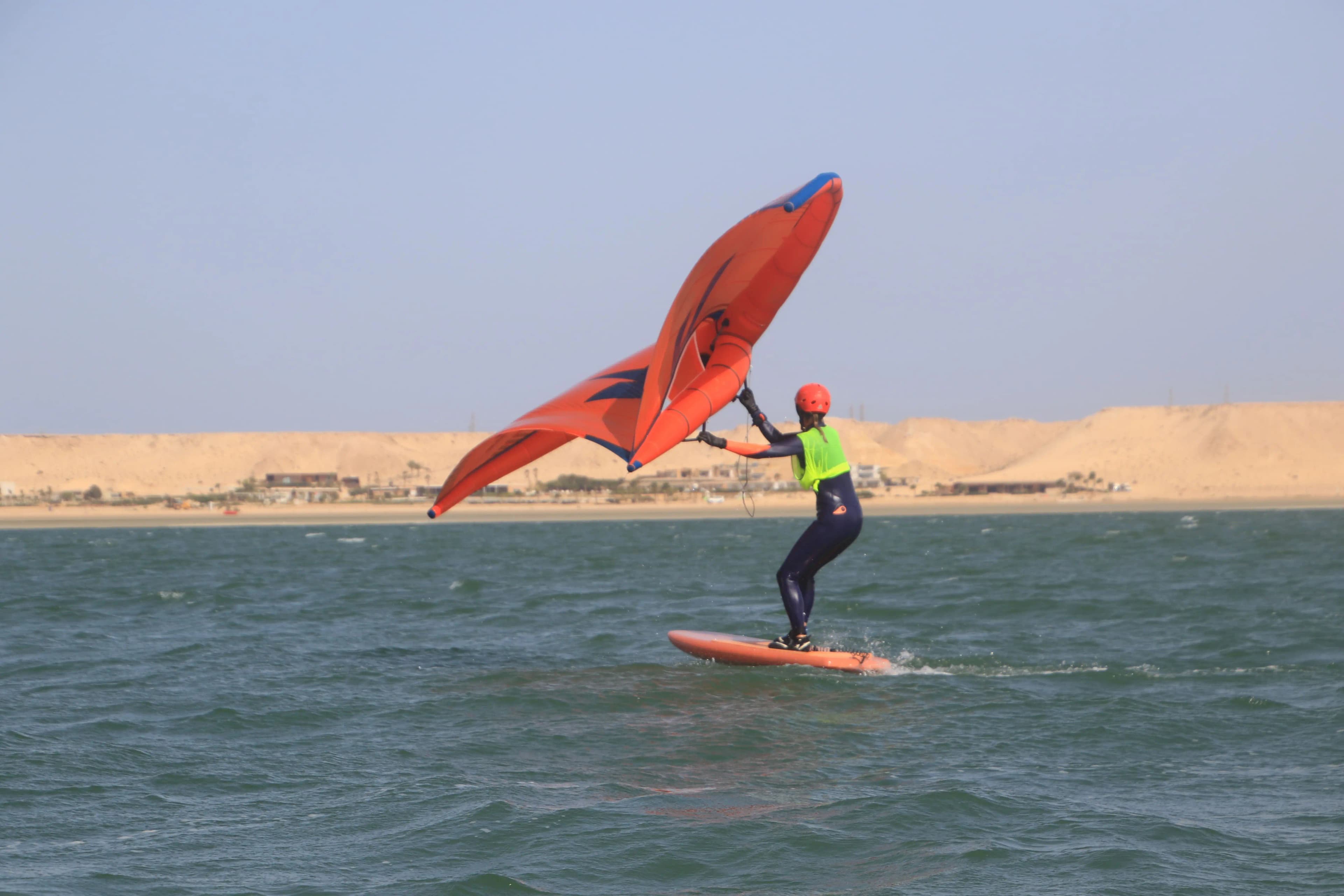 Un wingfoiler découvrant la sensation de vol, glissant en silence au-dessus du lagon de Dakhla avec Blüboarding.