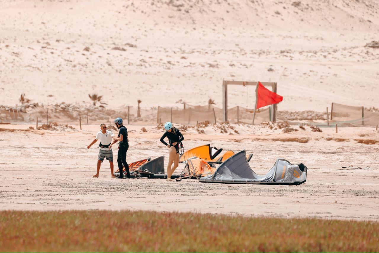 Membre de l'équipe Bluboarding partageant un moment convivial avec des clients kitesurf sur le bord du lagon de Dakhla avant d'aller sur l'eau pour une session de kitesurf.
