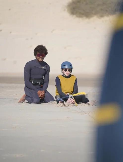 Bluboarding kitesurf instructor sitting next to a young student and teaching kite control on the flat water of the Dakhla lagoon during a private kitesurf lesson in Morocco.