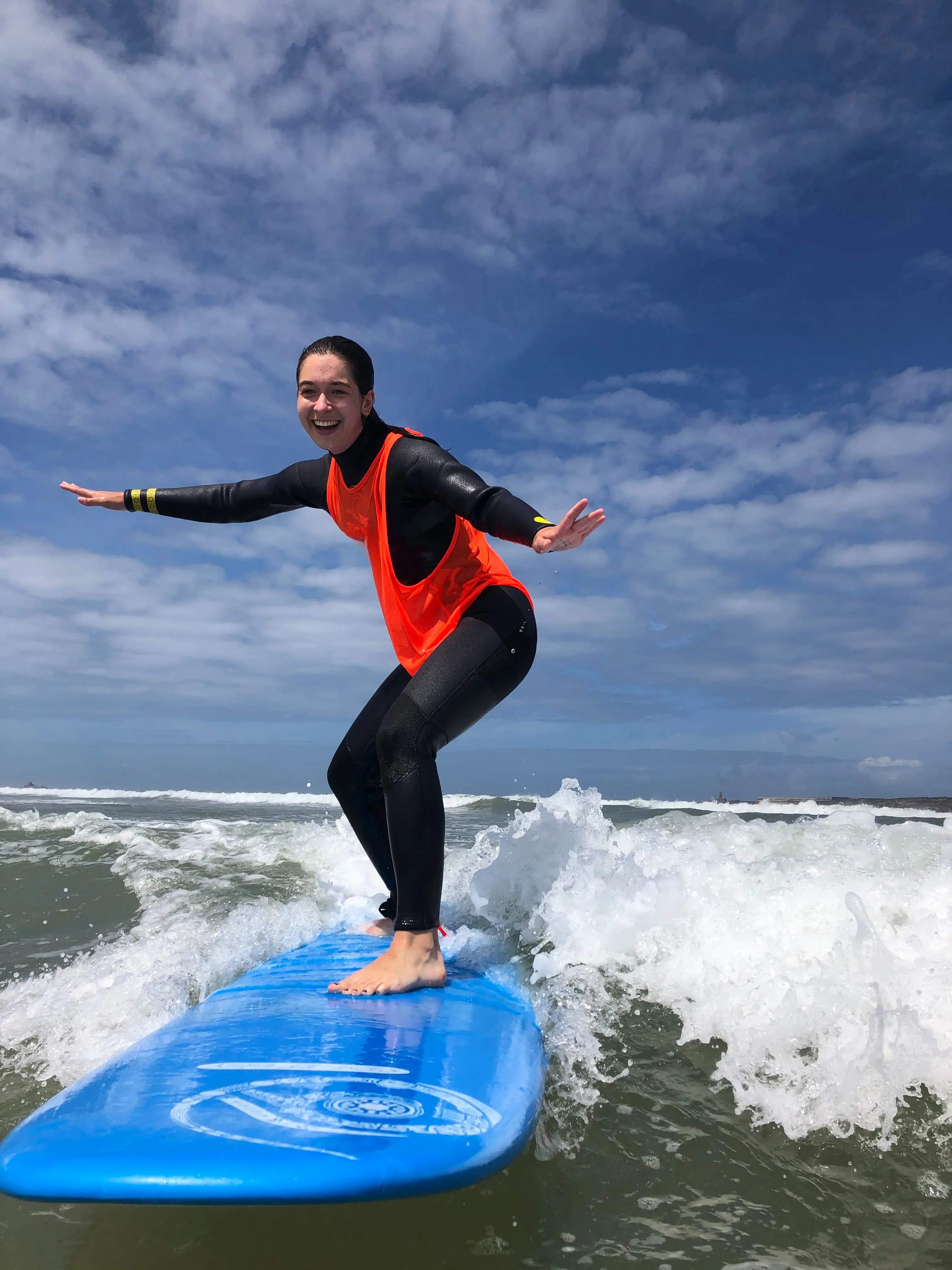 Happy Bluboarding surf student catching her first wave on the beach of Essaouira during a beginner surf lesson in Morocco.