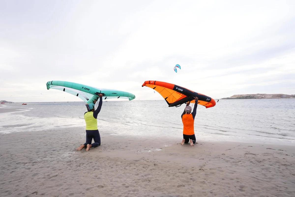 Two Bluboarding students practising wingfoil wing control together on the beach of Dakhla during a semi-private wingfoil lesson in Morocco.