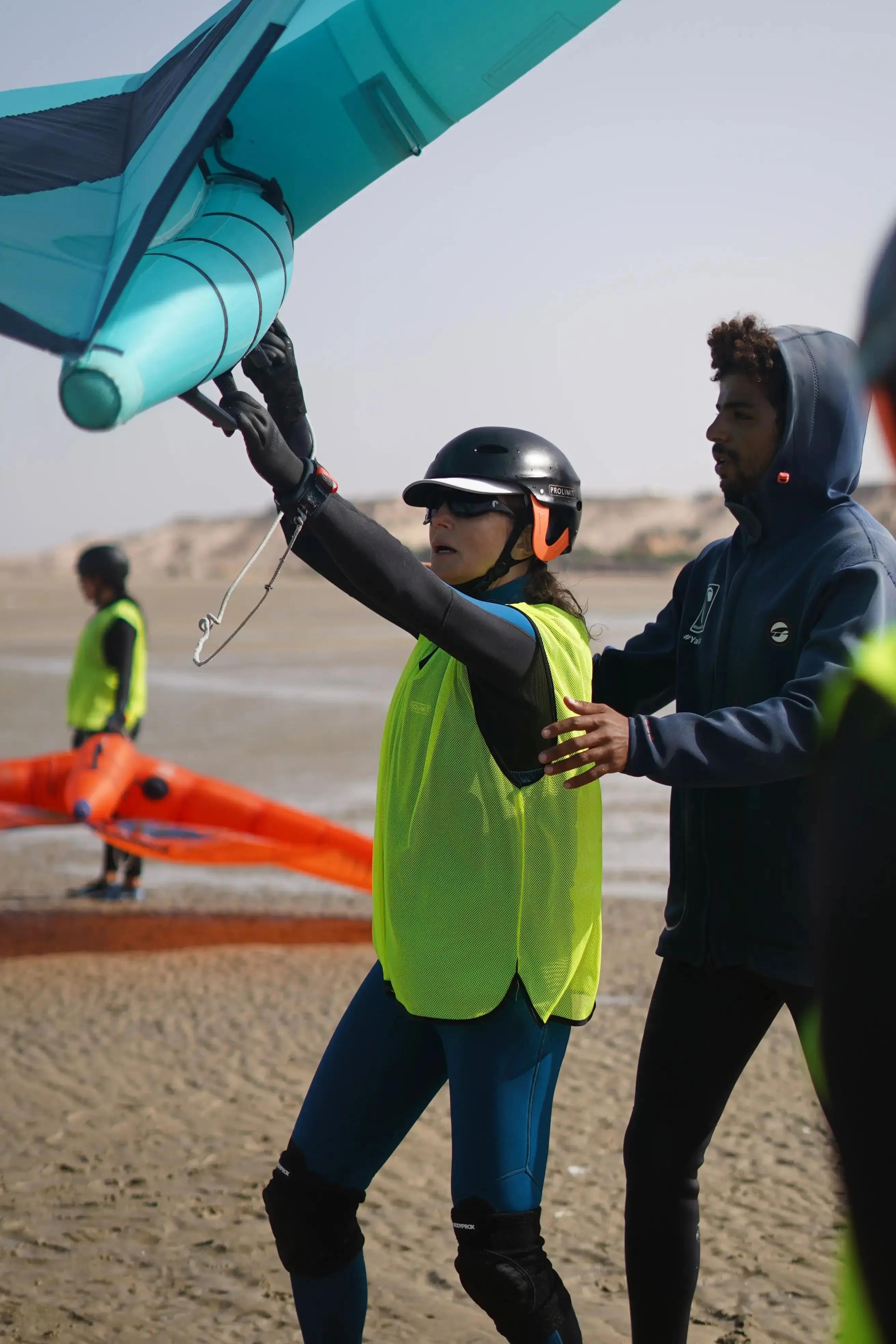 Bluboarding wingfoil instructor showing a woman student the correct hand position for optimal wing control during a group wingfoil lesson on the beach in Dakhla, Morocco.