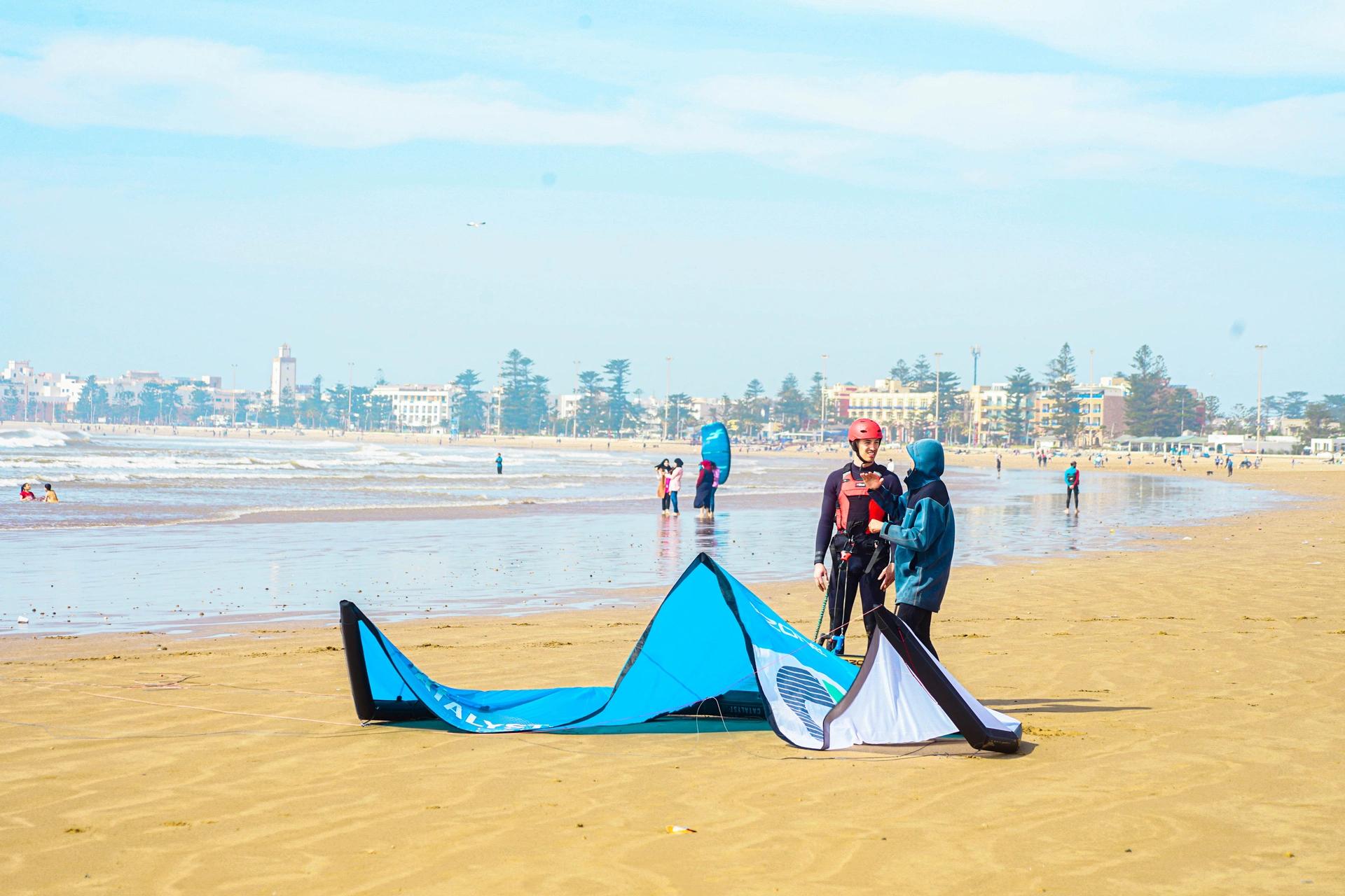 Moniteur kitesurf Bluboarding expliquant les bases à un élève débutant sur la plage d’Essaouira avant d’aller sur l’eau.