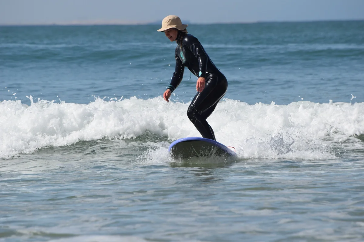 Bluboarding surf student catching a wave in the ocean at Aarich beach near Dakhla during a surf lesson in Morocco.