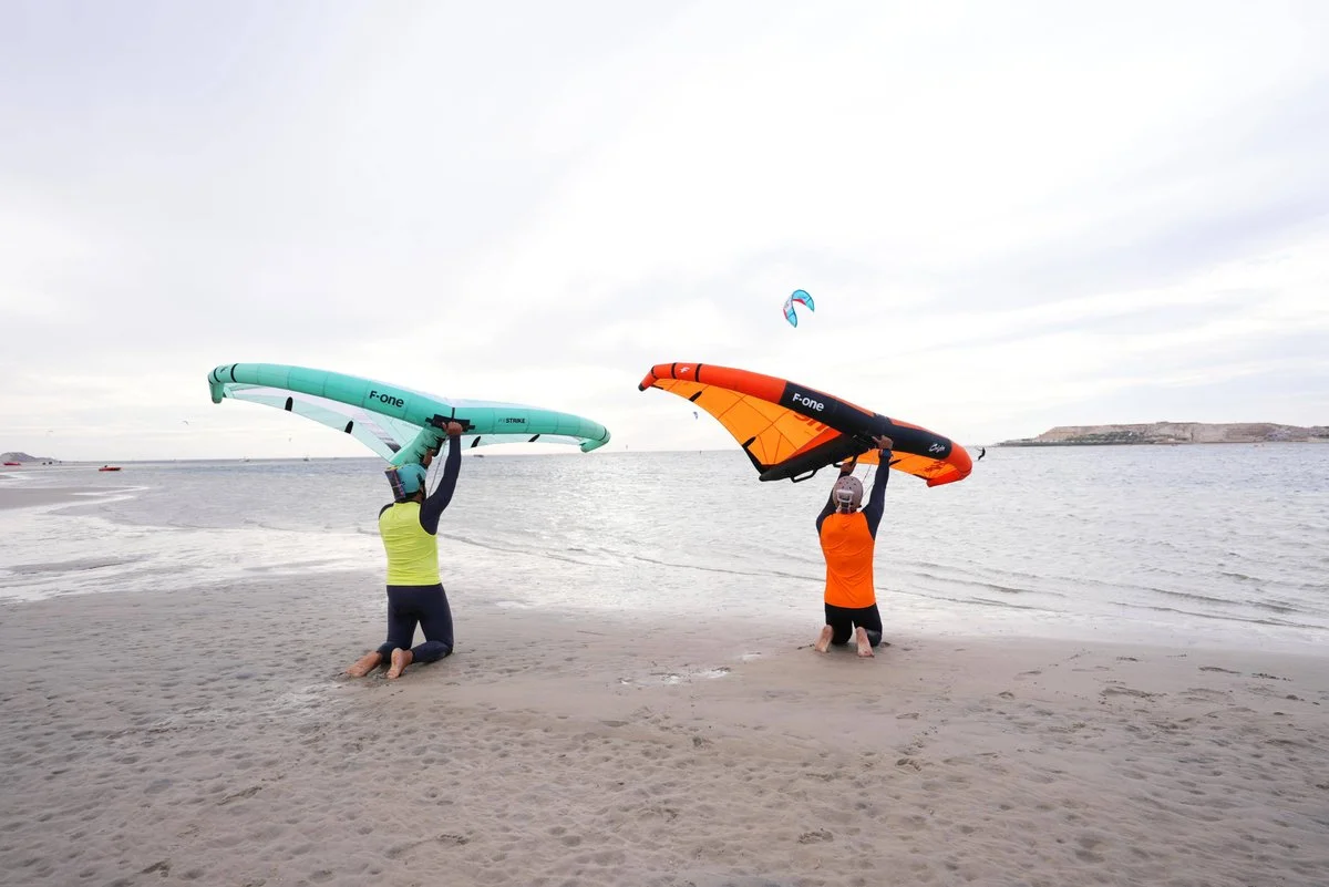 Two Bluboarding students practising wingfoil wing control on the beach of Dakhla before moving to the board during a wingfoil lesson in Morocco.