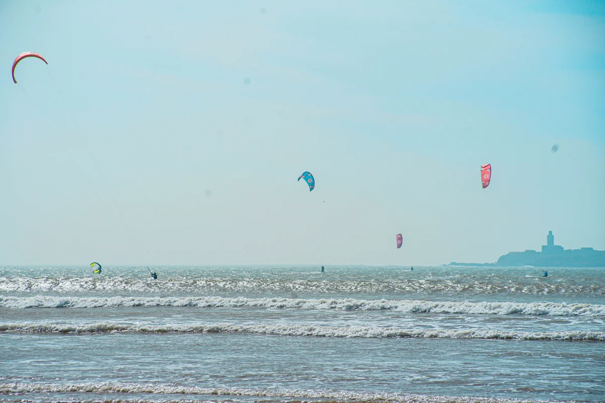 Clients Bluboarding en session de surf par une journée ensoleillée sur la plage principale d'Essaouira avec un vent alizé régulier sur la côte atlantique du Maroc.
